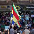 Protesting Syrians in the town of Suwayda hold signs and Druze flags - source: Reuters